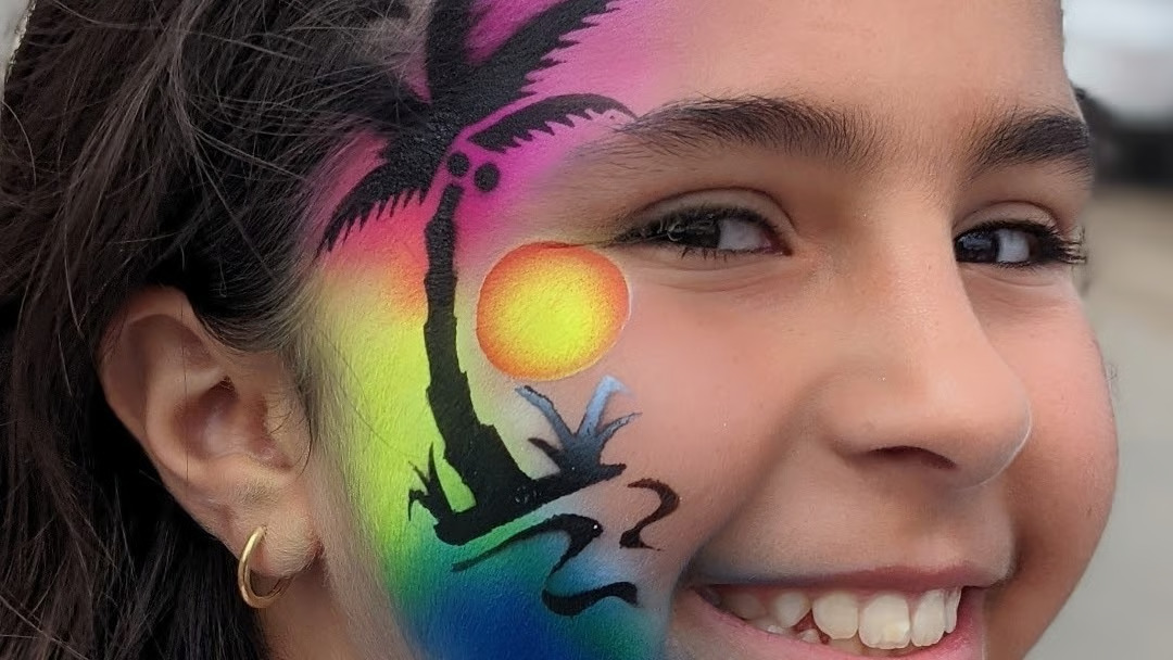 Professional face painter creating a colourful design
